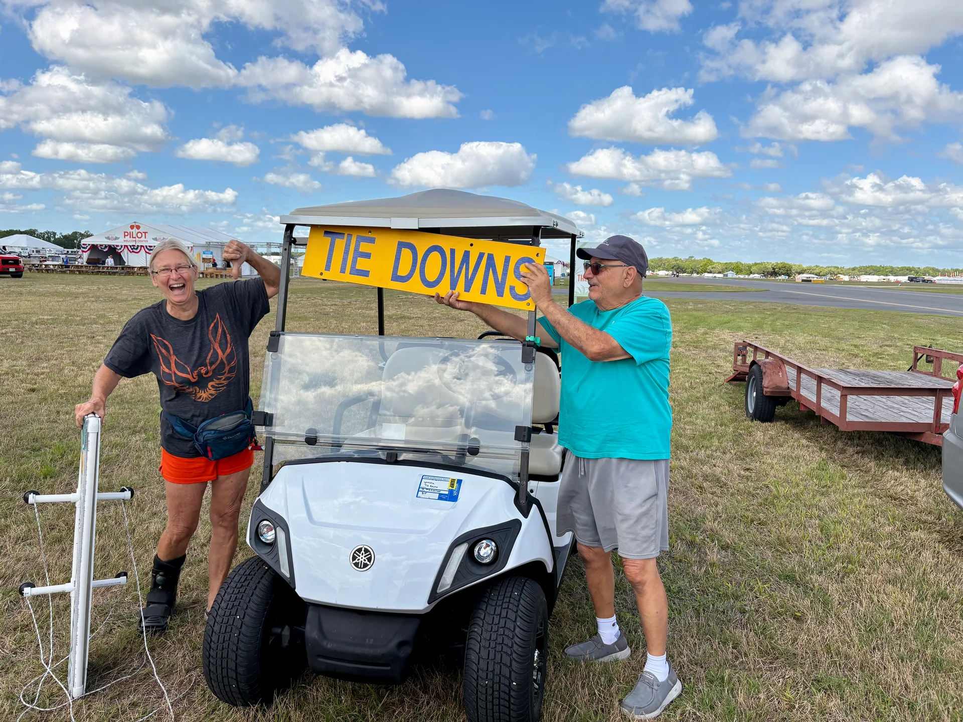 Two EAA Chapter 229 volunteers proudly holding the Tie Downs sign at Sun n Fun 2026