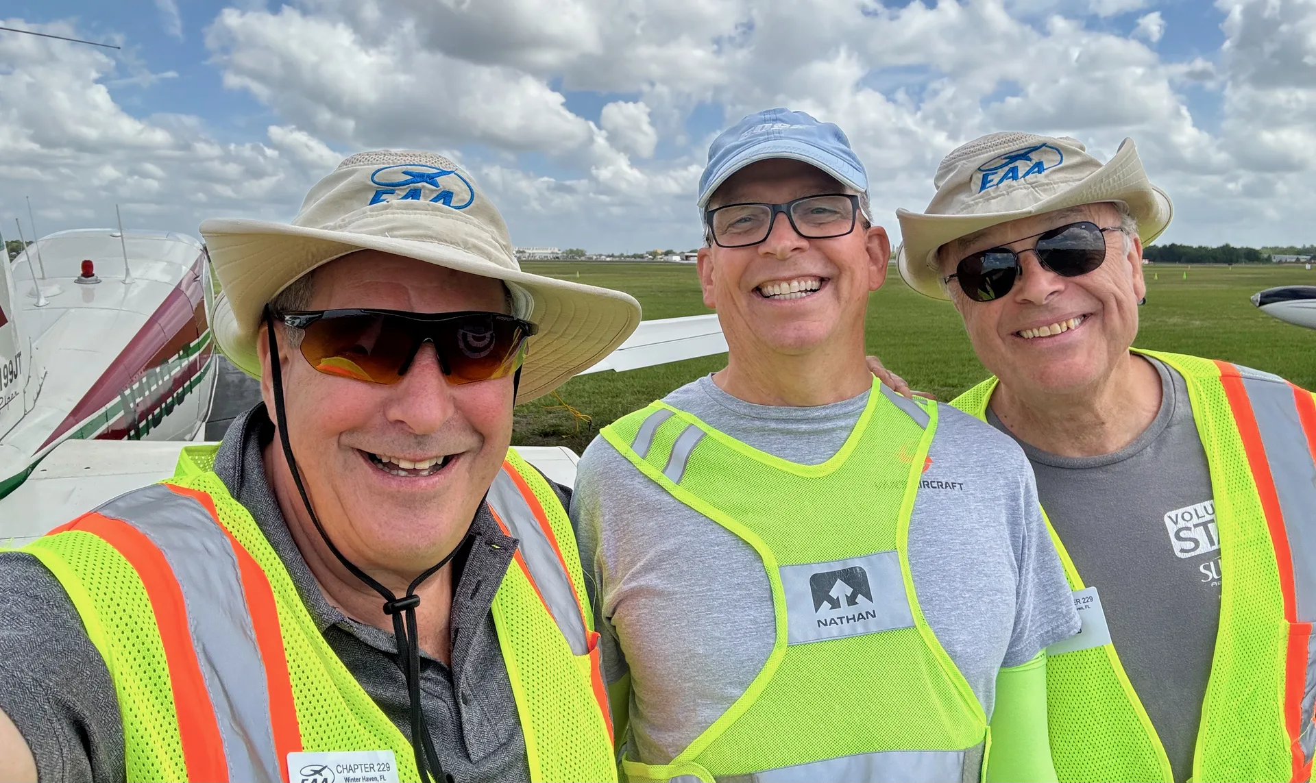 Three EAA Chapter 229 volunteers in safety vests and EAA hats during Sun n Fun 2026